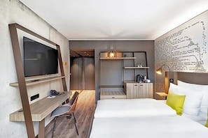 A modern hotel room with a large bed, a desk with a chair, a television, and a coffee machine. - The Cloud One Dresden-Frauenkirche (Dresden)