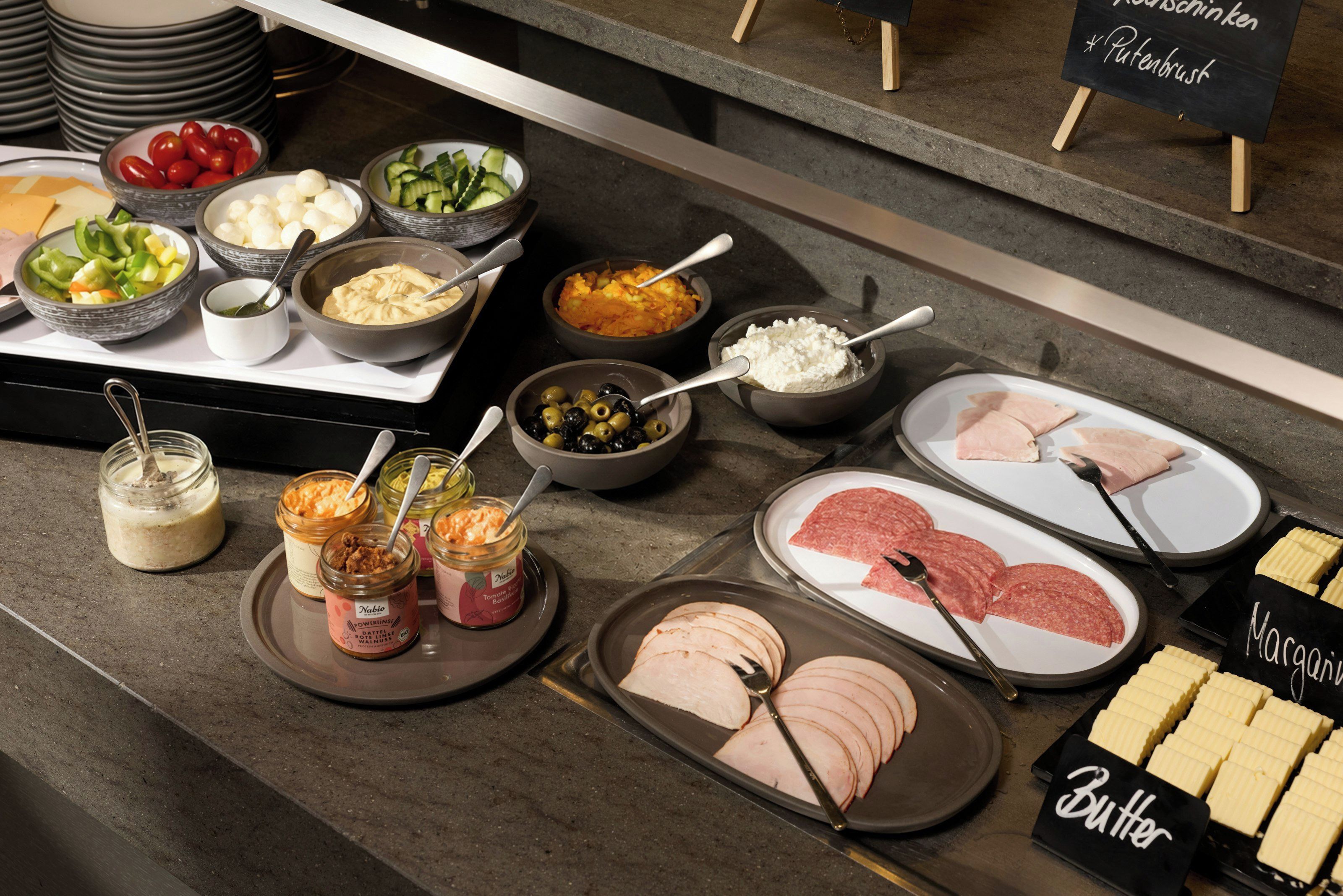 A buffet spread with various food items including meats, cheeses, and condiments.
