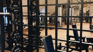 A gym with weightlifting equipment, a bench, and a mirror reflecting the interior.