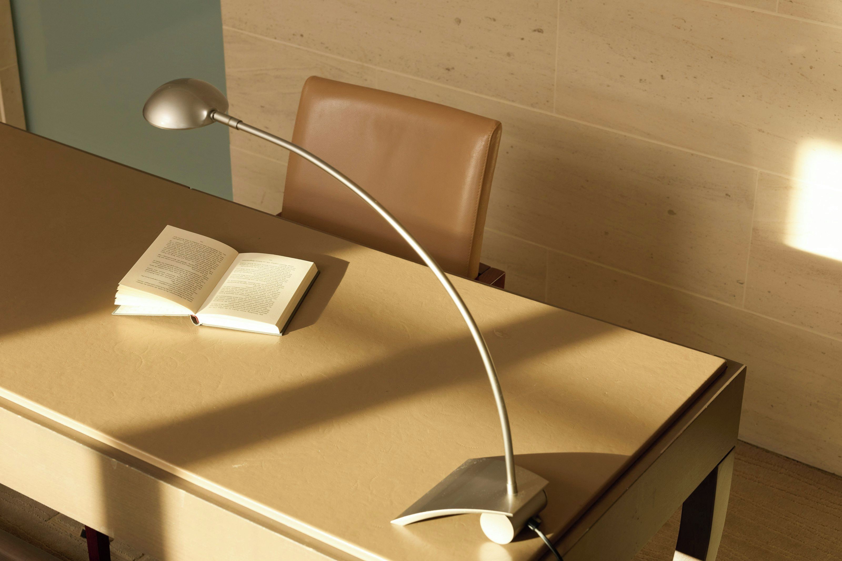 Un bureau avec un livre ouvert, une lampe de bureau et une chaise.