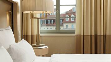 A hotel room with a bed, a lamp, and a window with curtains.