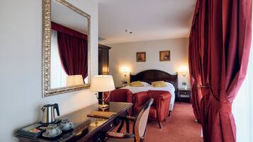 A hotel room with a large bed, a desk with a lamp, a chair, and a mirror.