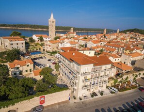A coastal town with historic architecture, including a prominent tower and a hotel with balconies. - Arbiana Heritage Hotel (Rab)