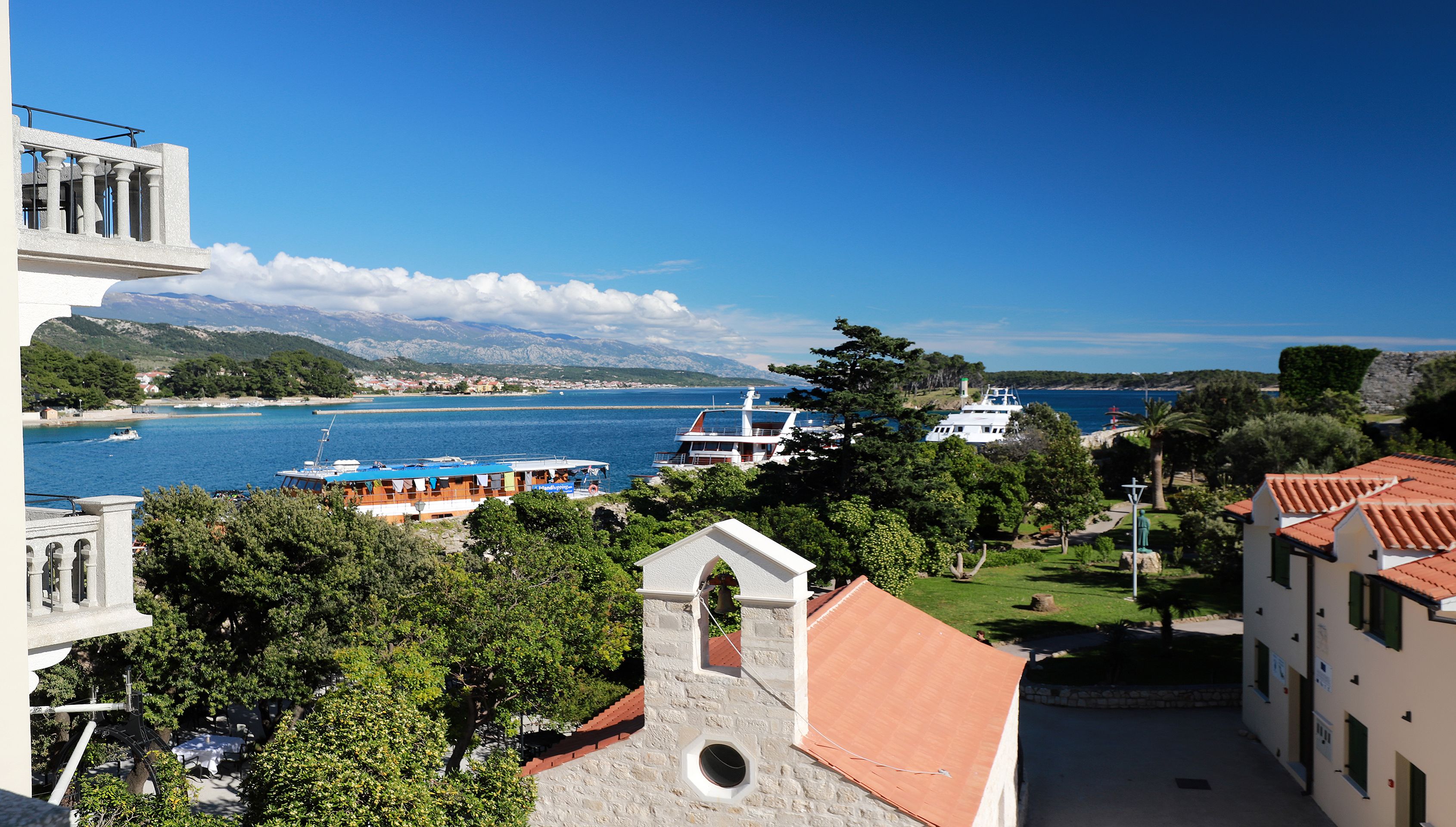 Une vue sur la côte, avec une église, un bateau et un bâtiment doté d’un toit rouge.