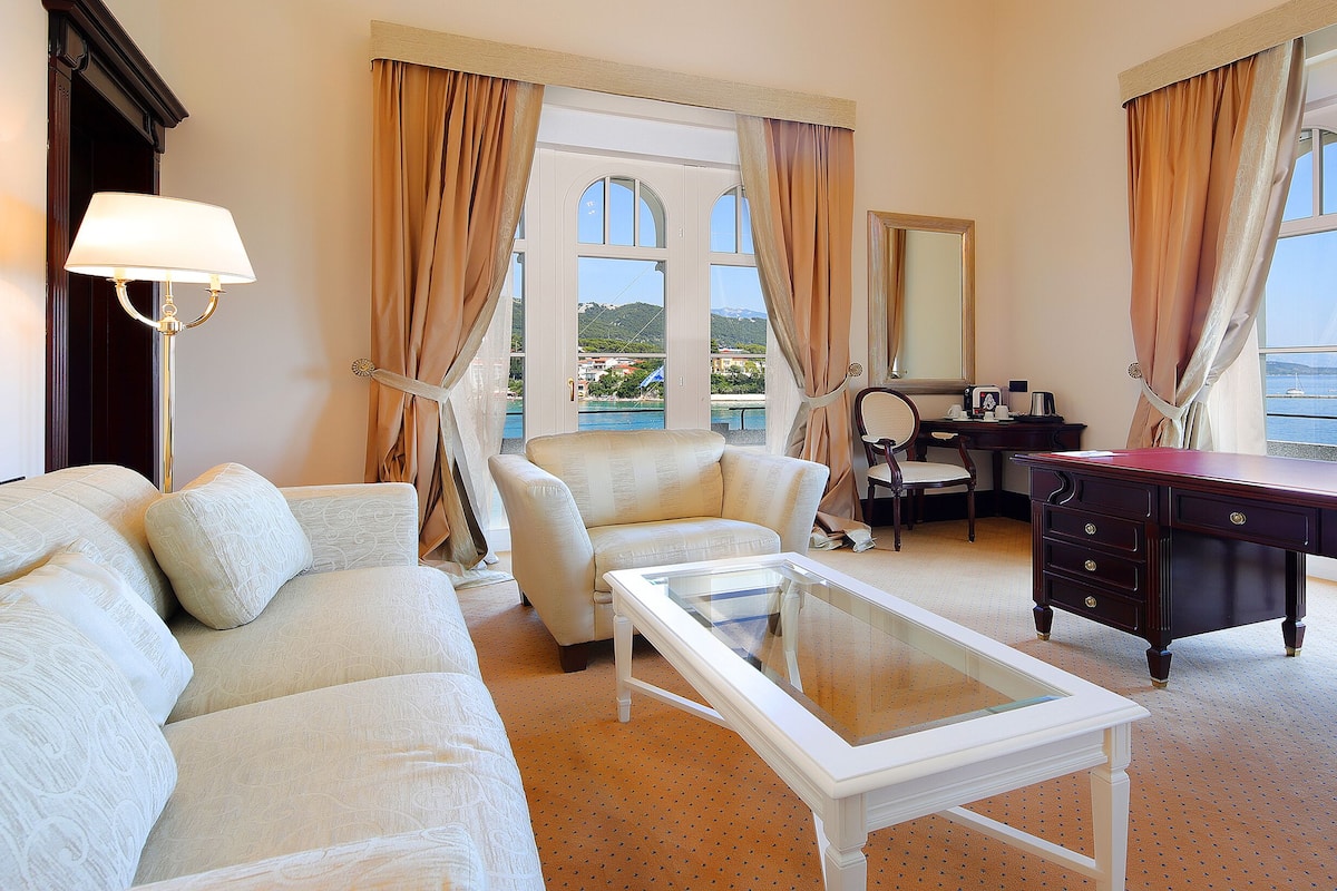 Une chambre d’hôtel équipée d’un canapé, d’un fauteuil, d’un bureau et offrant une vue sur la mer.