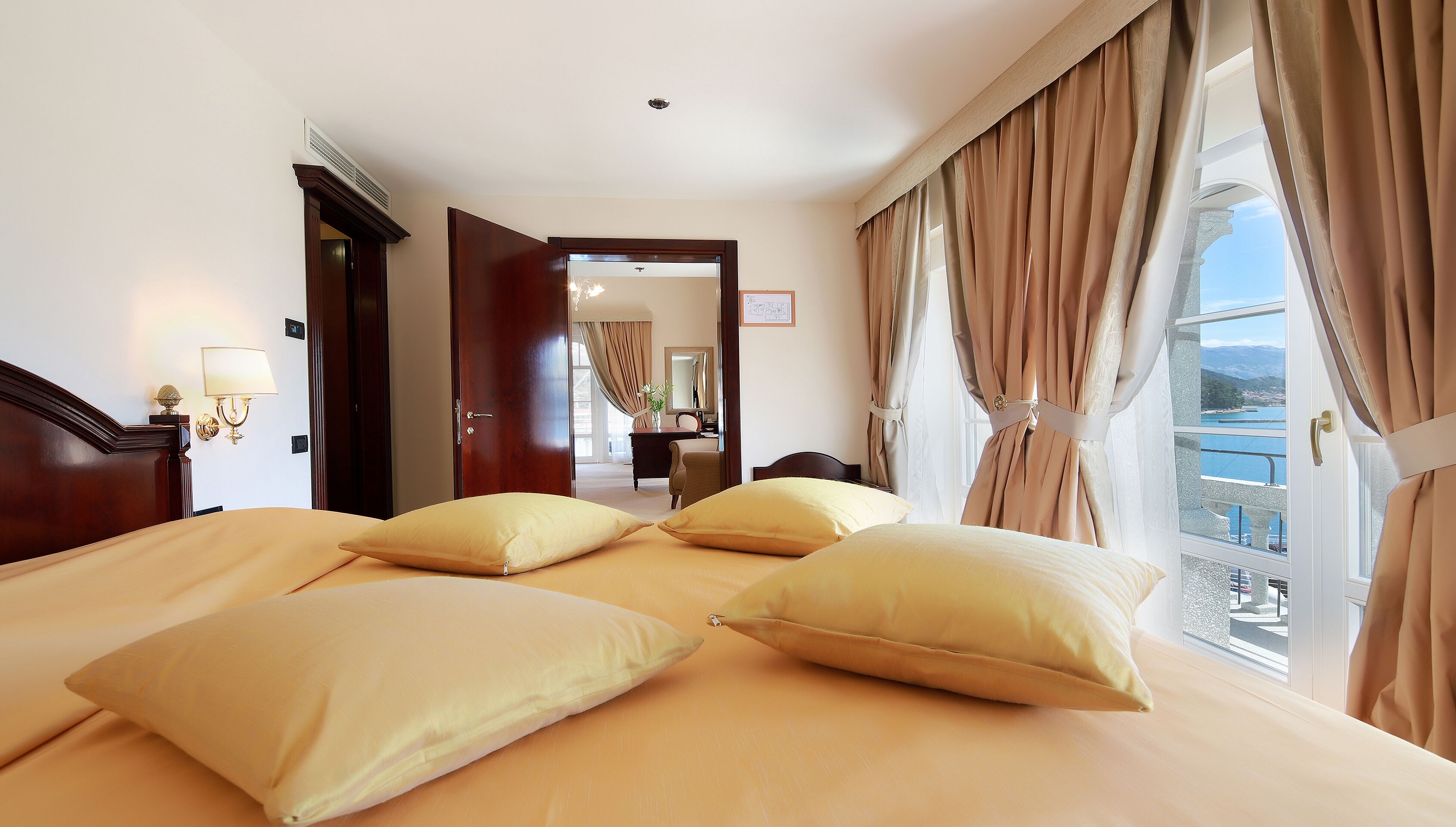 A hotel room with a large bed, a desk, and a view of the sea.
