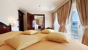 A hotel room with a large bed, a desk, and a view of the sea.