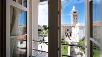 A view from a balcony with a stone building and a tower in the background.