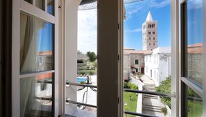 A view from a balcony with a stone building and a tower in the background. - Arbiana Heritage Hotel (Rab)