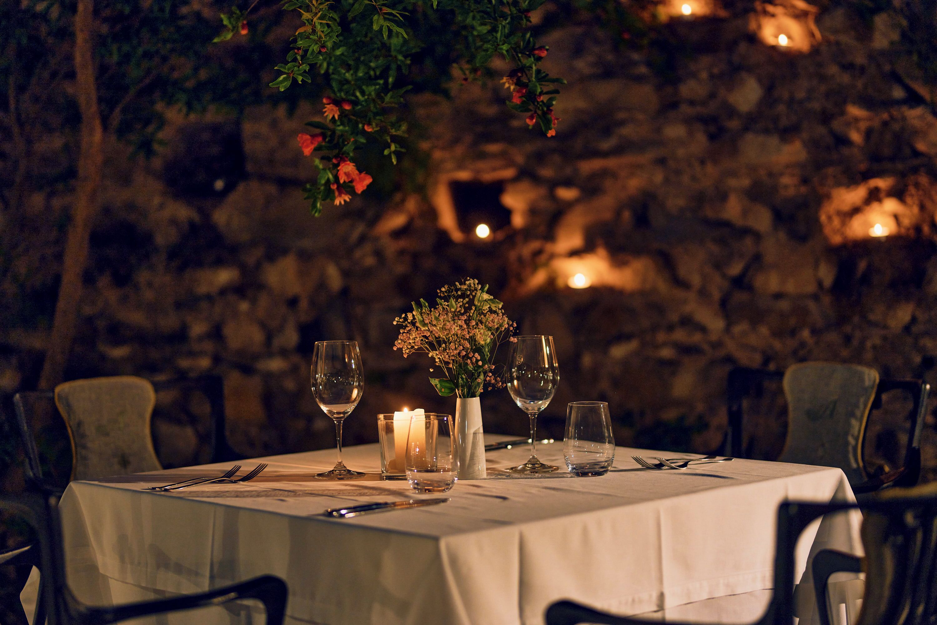 A table set for dining with candles, glasses, and a vase of flowers.