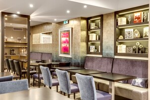 Un restaurante moderno con diversas opciones de asientos, incluyendo mesas y cabinas, y una pared decorada con obras de arte y adornos.