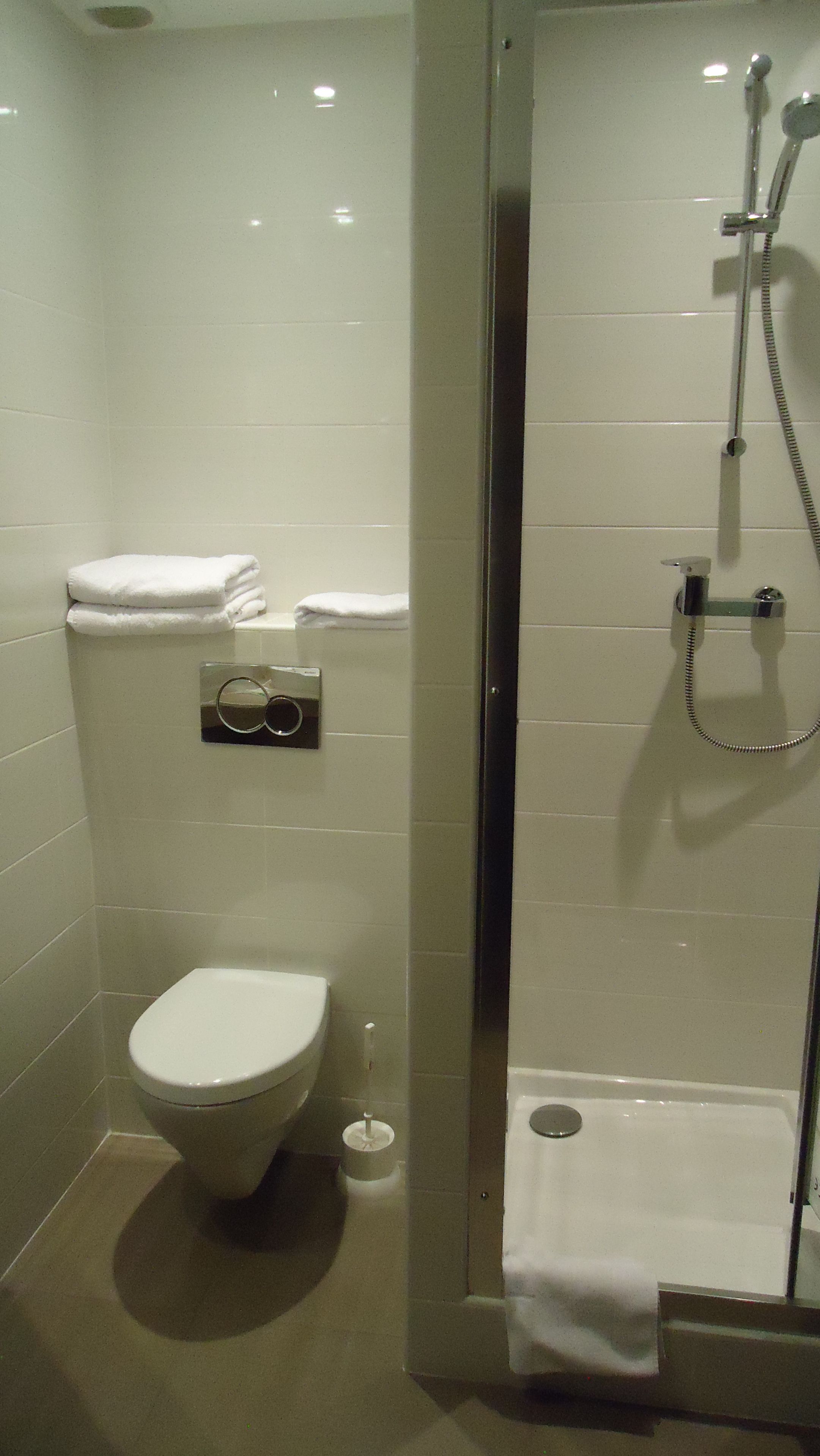 Un baño moderno con inodoro, ducha y perchero para toallas.