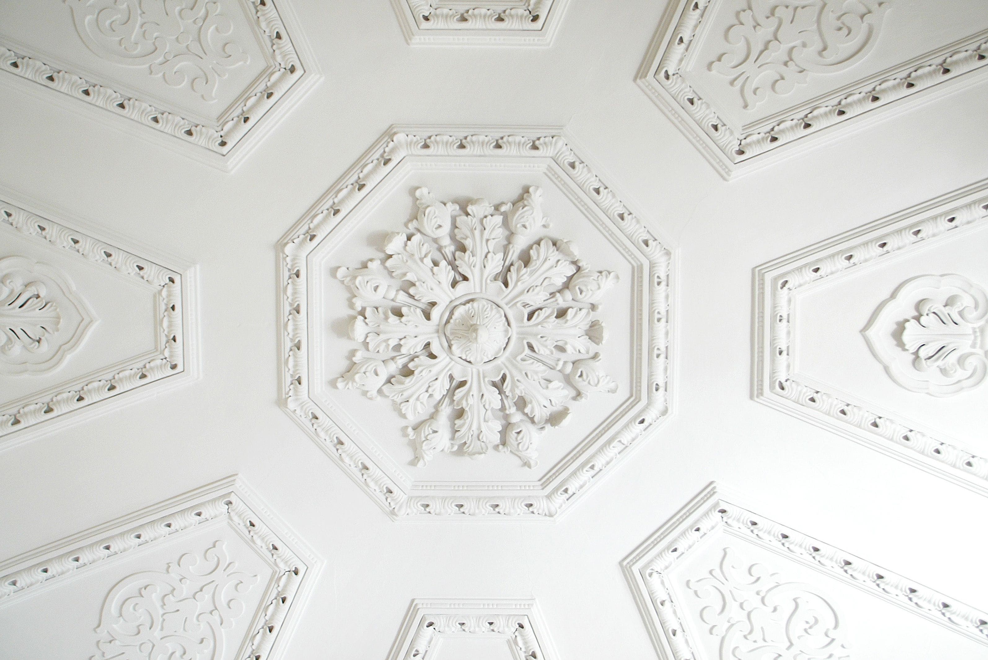 A ceiling with ornate, symmetrical, white, octagonal, and hexagonal patterns.