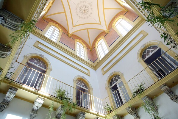 Ein mehrgeschossiges Atrium mit Balkonen, großen Fenstern und dekorativen Verzierungen.
