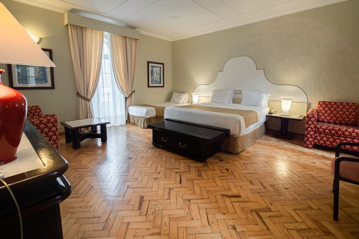 A hotel room with a large bed, a desk, a chair, and a sofa.