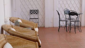 A room with wicker furniture and metal chairs.