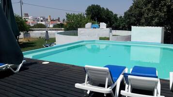 Una piscina al aire libre, sillones reclinables de piscina
