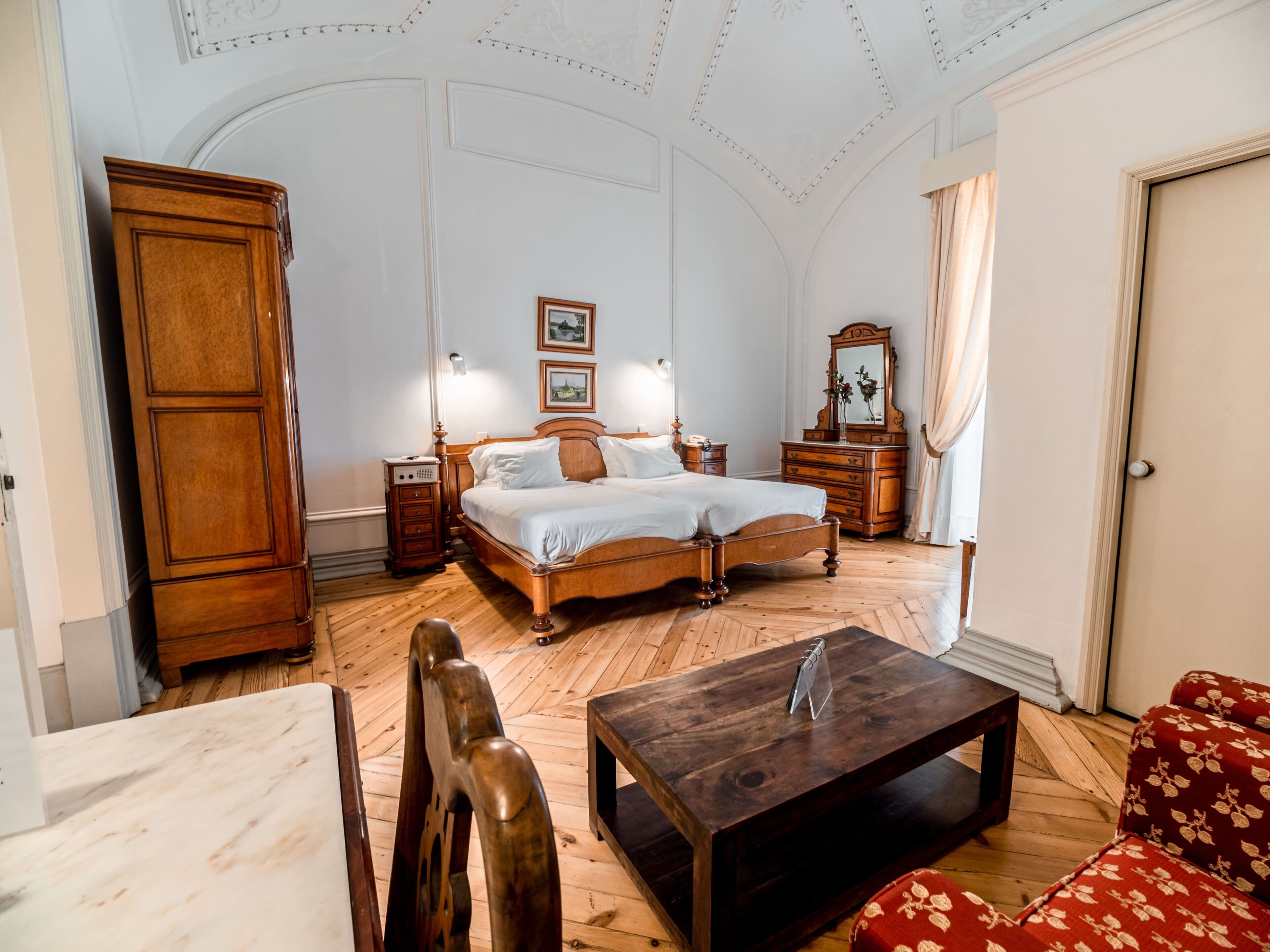 Une chambre à coucher avec un lit en bois, une table de chevet, une commode, un miroir et un canapé rouge.