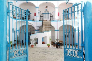 Ein Innenhof mit Treppe, Blumentöpfen und Sitzgelegenheiten im Freien.