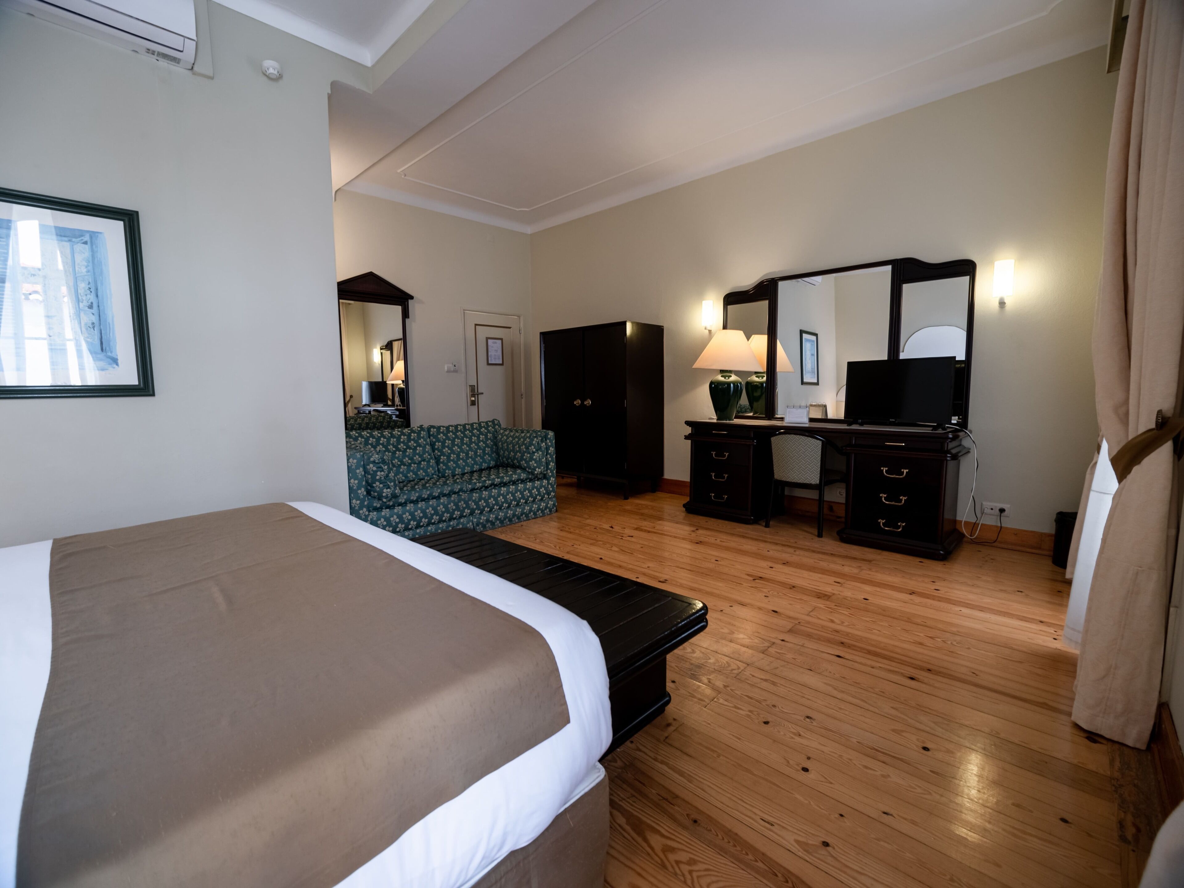 Una habitación de hotel con una cama grande, un escritorio con silla, un sofá y un aparador.