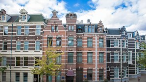 A row of traditional European-style buildings with uniform facades, a central entrance, and a paved courtyard. - Hotel Roemer (Amsterdam)