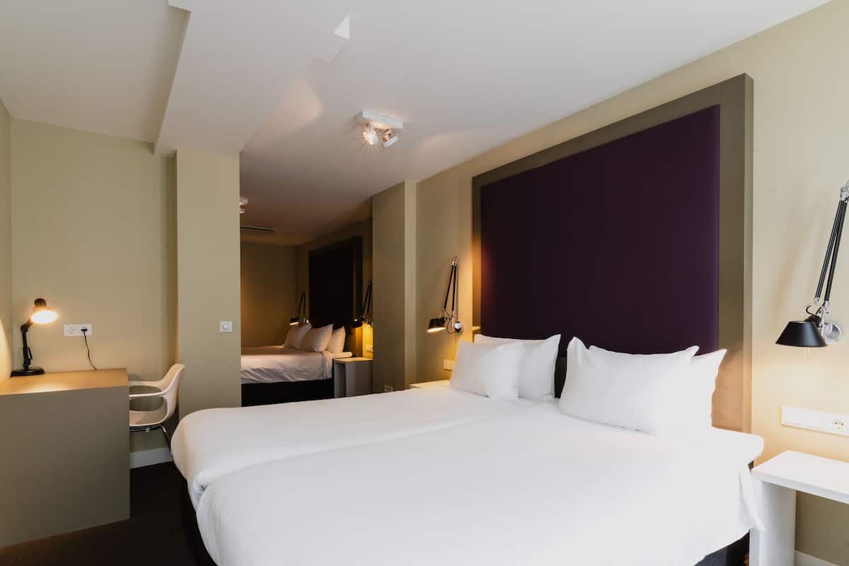 A hotel room with a large bed, bedside tables, a desk, and a chair.