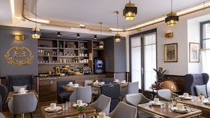 Uma sala de jantar moderna com mesas preparadas para o serviço, área de bar com prateleiras e um globo decorativo grande.