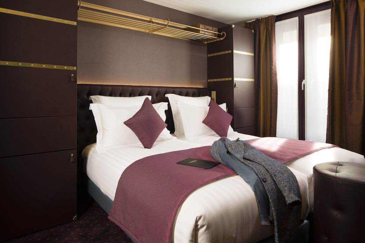 A hotel room with a large bed, a headboard, a bedside table, and a wardrobe.