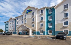 A multi-story hotel with a prominent sign, a covered entrance, and a parking lot.