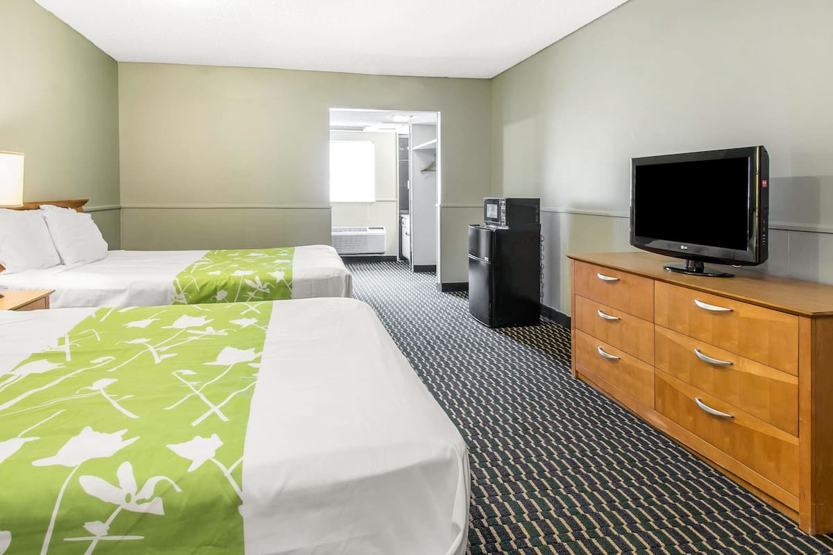 A hotel room with two beds, a television, a minibar, and a wardrobe.