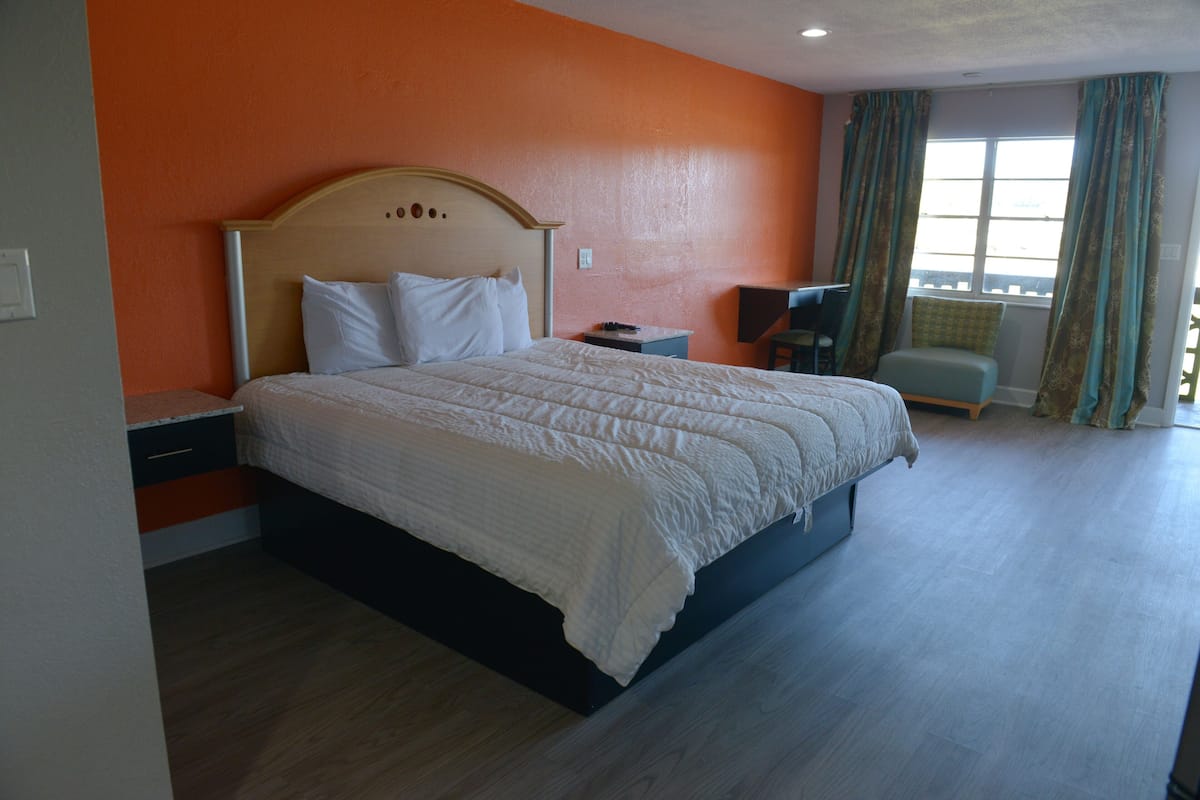 A hotel room with a large bed, a desk, and a chair.