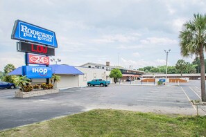 A parking lot with a sign for Rodeway Inn & Suites, a 24-hour I-HOP convenience store, and a blue pickup truck parked in the lot. - Rodeway Inn & Suites Winter Haven Chain Of Lakes (Winter Haven)