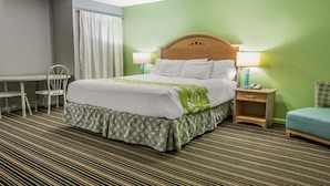 A hotel room with a bed, two bedside tables, a desk, a chair, and a blue armchair.