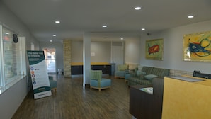 A reception area with a wooden floor, seating arrangements, and a reception desk.