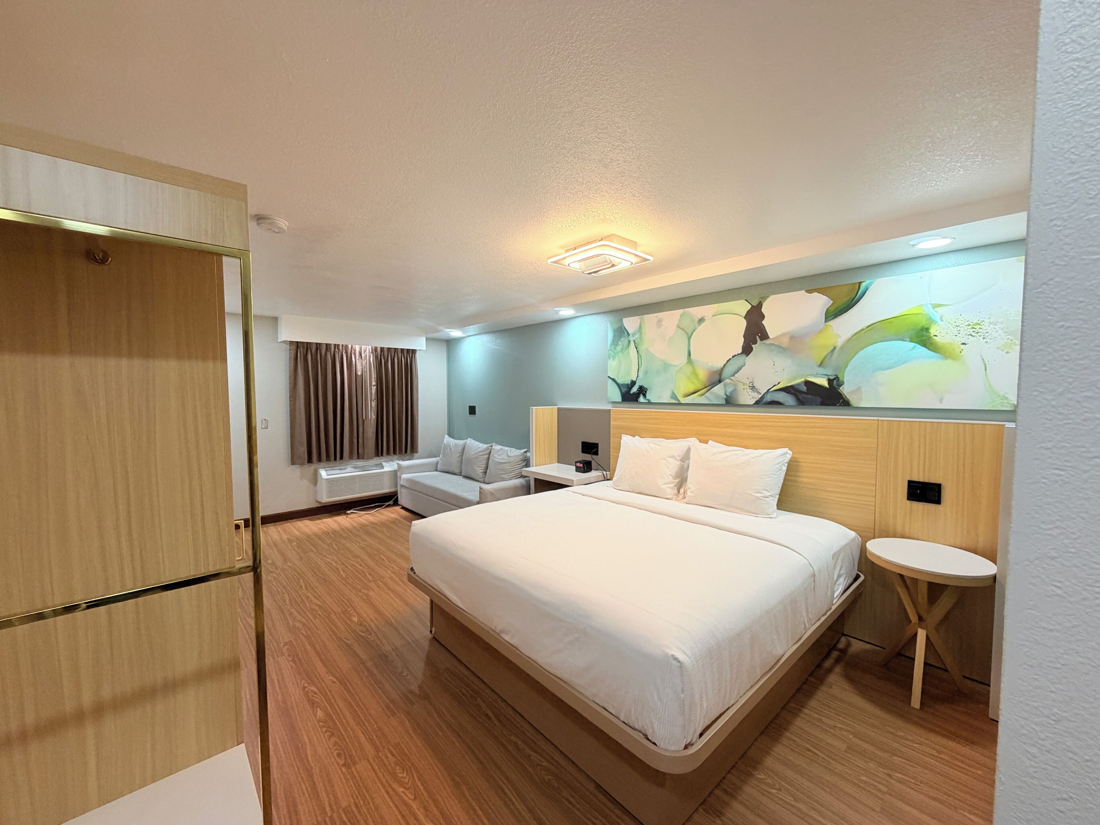 A hotel room with a bed, a sofa, a small table, and a wardrobe.