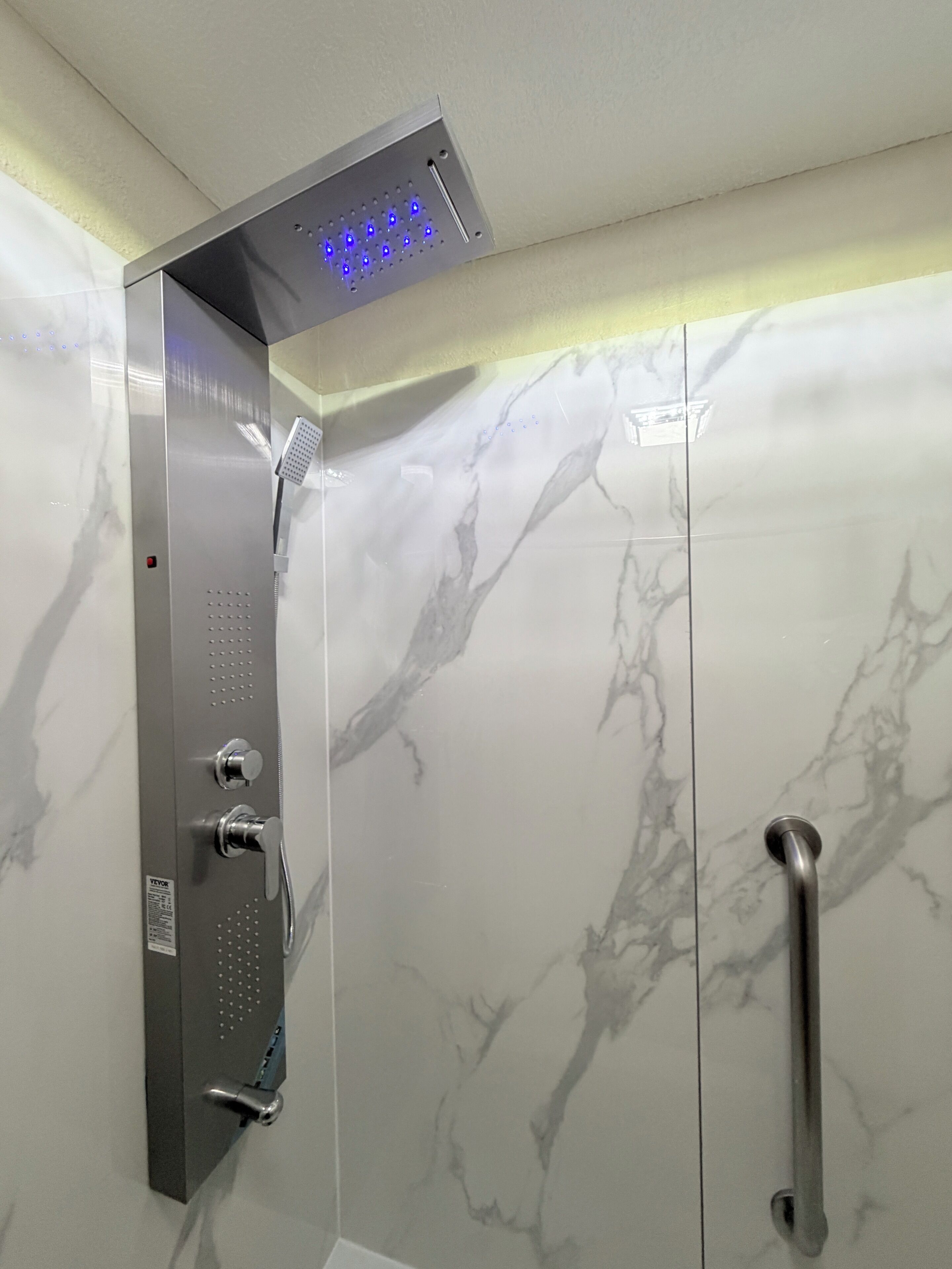 A shower with a digital display, a handheld showerhead, and a handheld shower bar.
