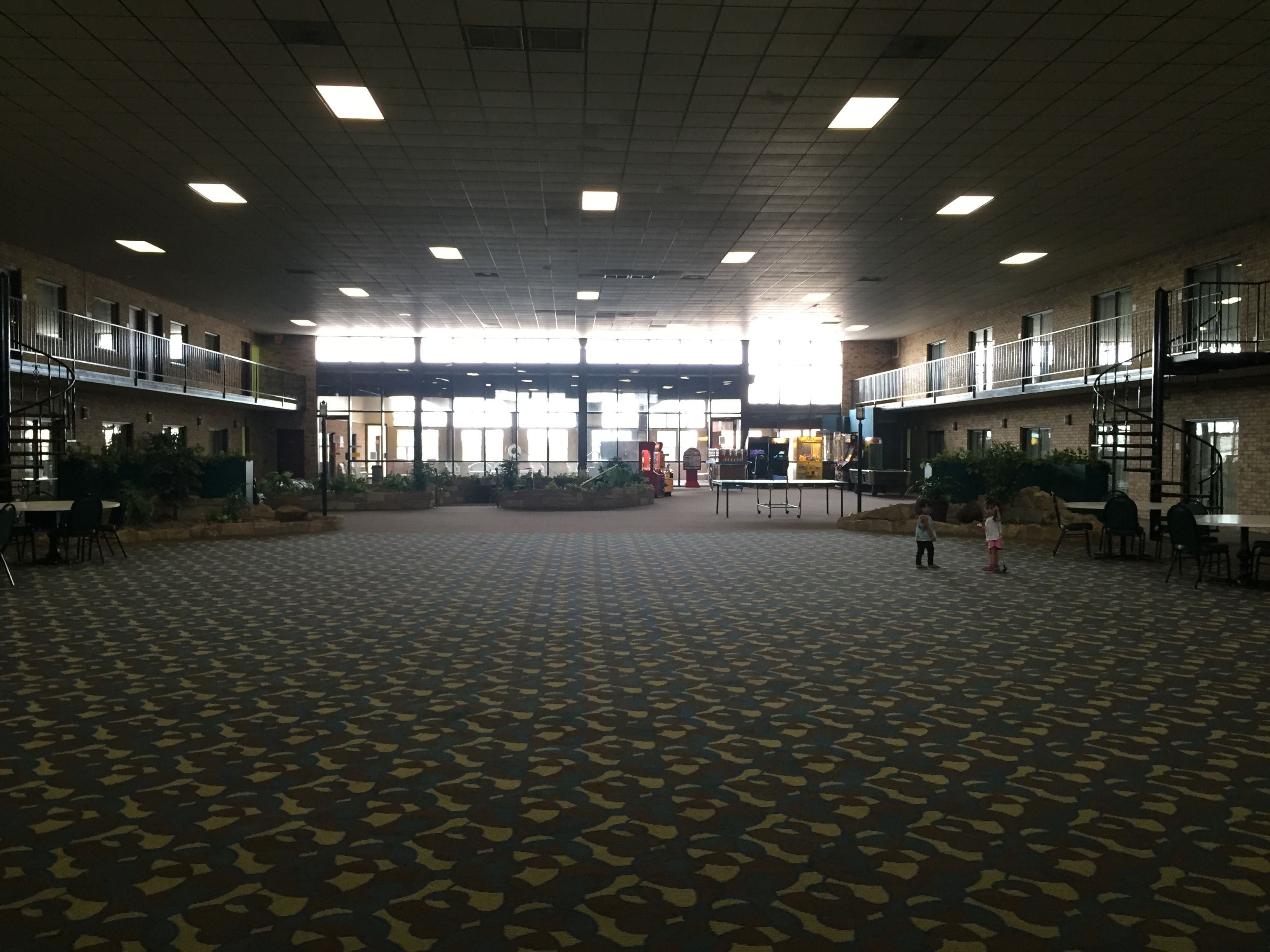 A spacious indoor area with a patterned carpet, multiple tables and chairs, and a central table.