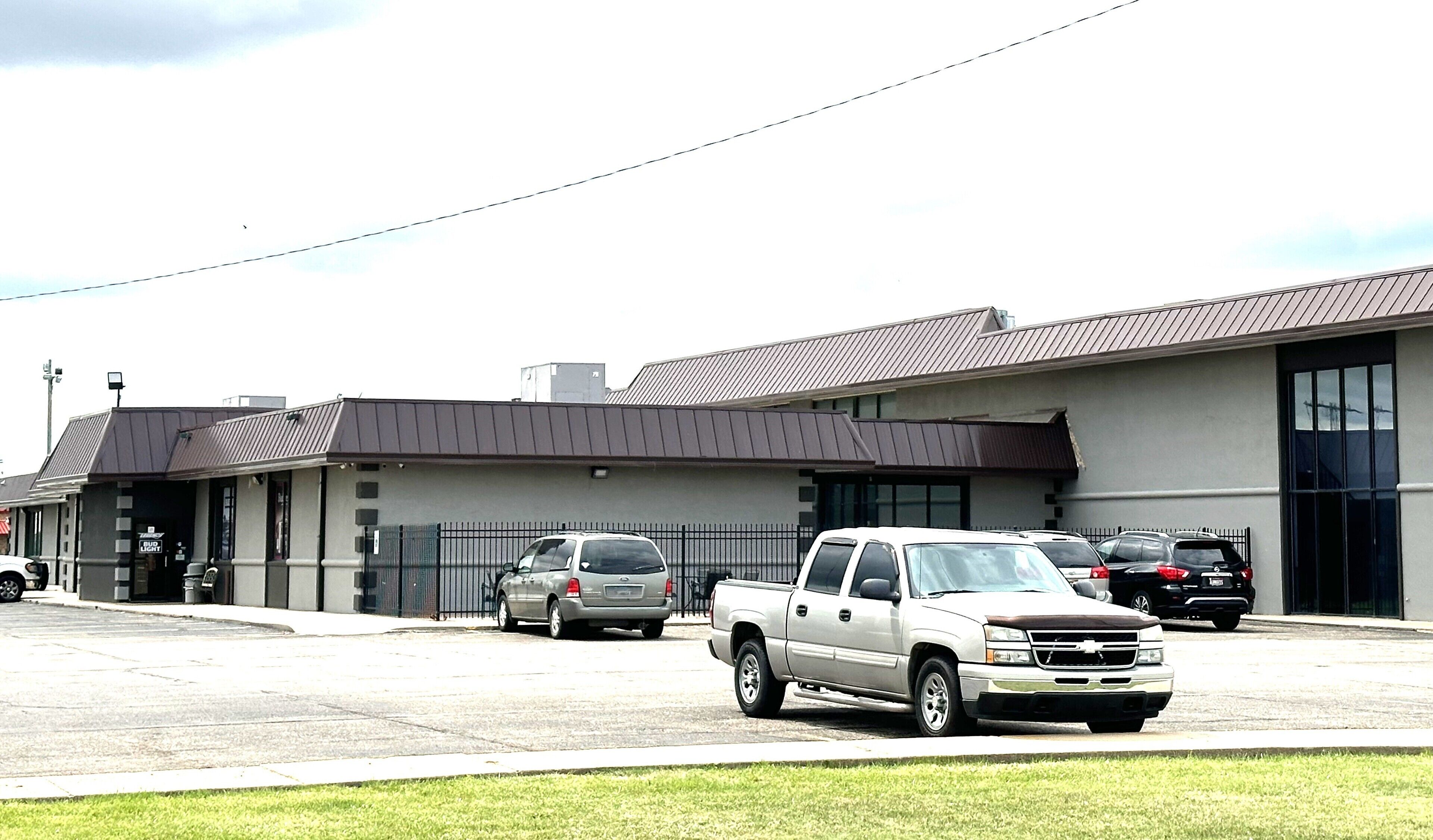 A building with a parking lot, a white pickup truck, and a grey car.
