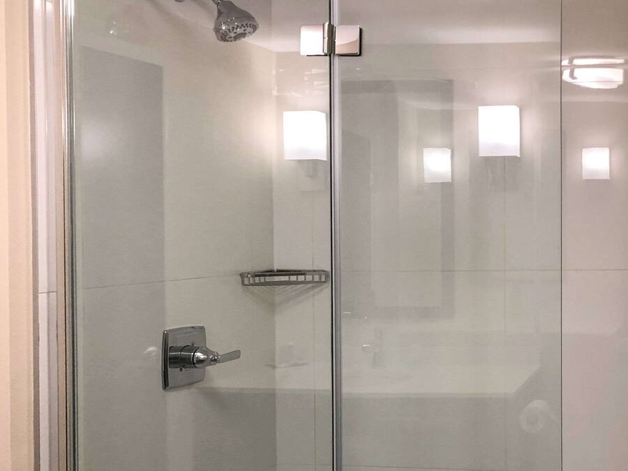 Un baño moderno con cabina de ducha de vidrio, grifo cromado y un estante pequeño.