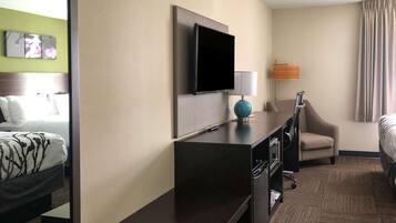Una habitación de hotel con una cama, un escritorio, una silla, un televisor y una lámpara.