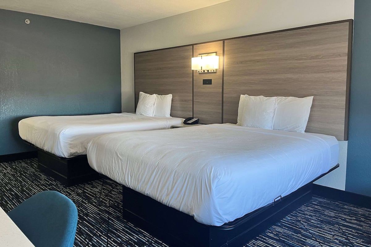 Habitación de hotel con dos camas, un escritorio y una silla.