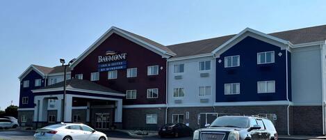 Ein Baymont Inn & Suites Hotel mit einem zweistöckigen Gebäude, einem überdachten Eingangsbereich und einem Parkplatz mit Autos.