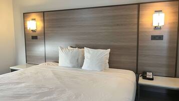A hotel room with a large bed, two bedside tables, and wall-mounted light fixtures.