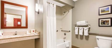 A bathroom with a sink, mirror, shower, and toilet.