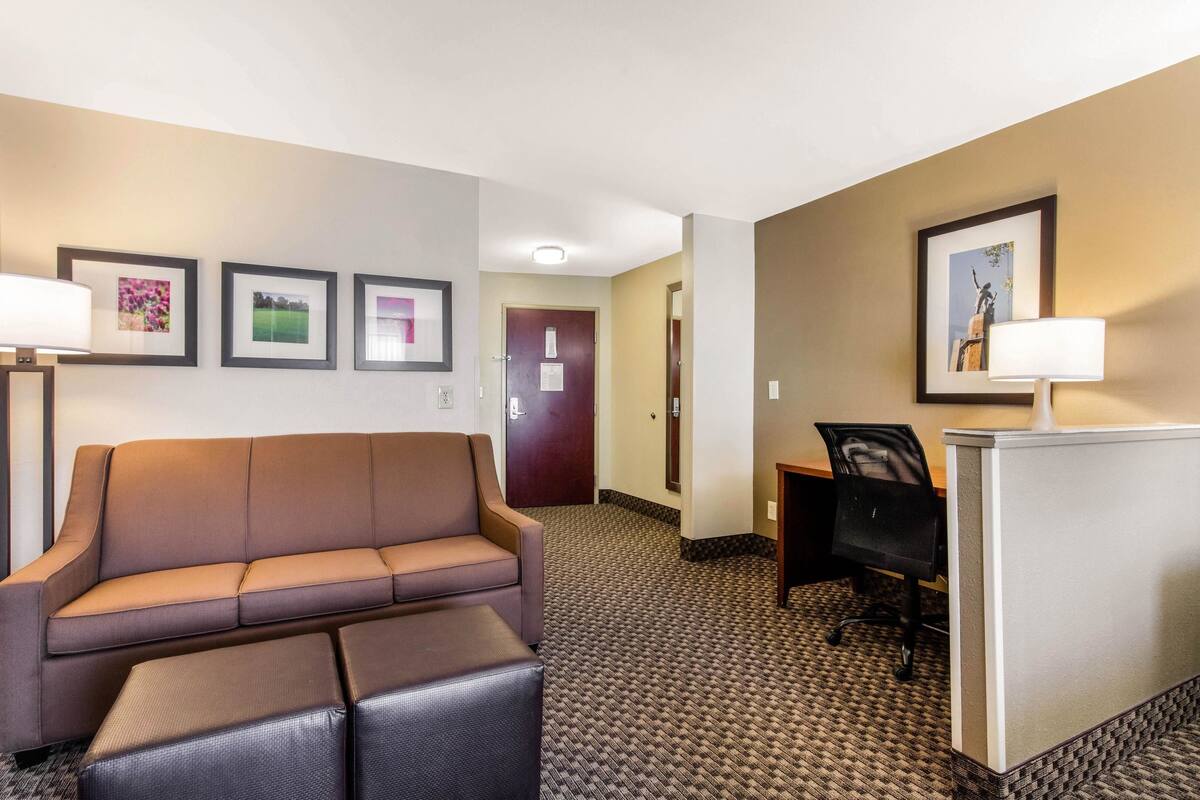A hotel room with a sofa, a small table, a desk, and a chair.