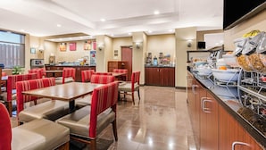 A restaurant with booths and tables, a buffet area, and a kitchen in the background. - Comfort Suites Tuscaloosa near University (Tuscaloosa)