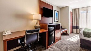A hotel room with a desk, chair, television, minibar, and a bed. - Comfort Suites Tuscaloosa near University (Tuscaloosa)
