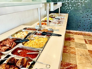 Buffet com diversos alimentos e utensílios.