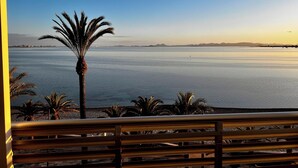A view of a calm body of water with a distant shoreline, palm trees, and a clear sky. - Hotel Neptuno (San Pedro del Pinatar)