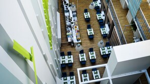 Een interieur van een meerlaags commercieel pand met open kantoorruimtes, vergaderruimtes en een centraal atrium.
